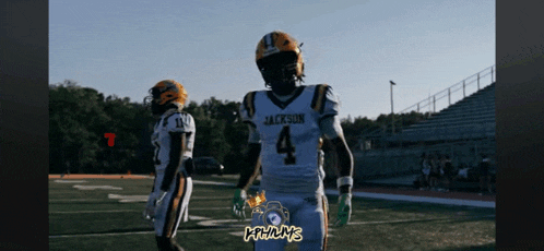 a football player wearing a jackson jersey walks on the field