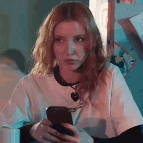 a woman is sitting at a table holding a cell phone .