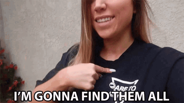 a woman is pointing at a shirt that says " i 'm gonna find them all "