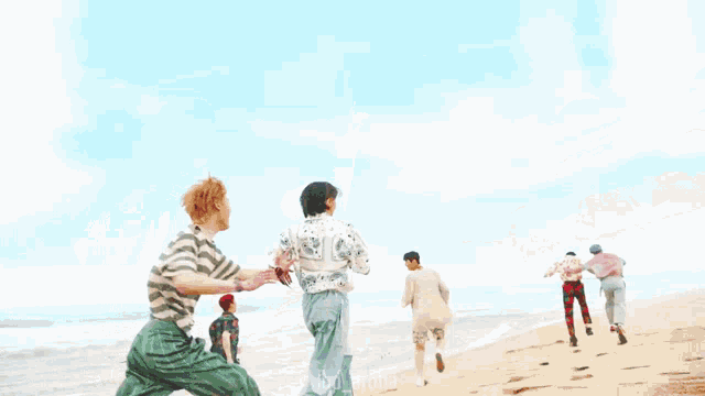 a group of people are walking on a beach with their arms outstretched .