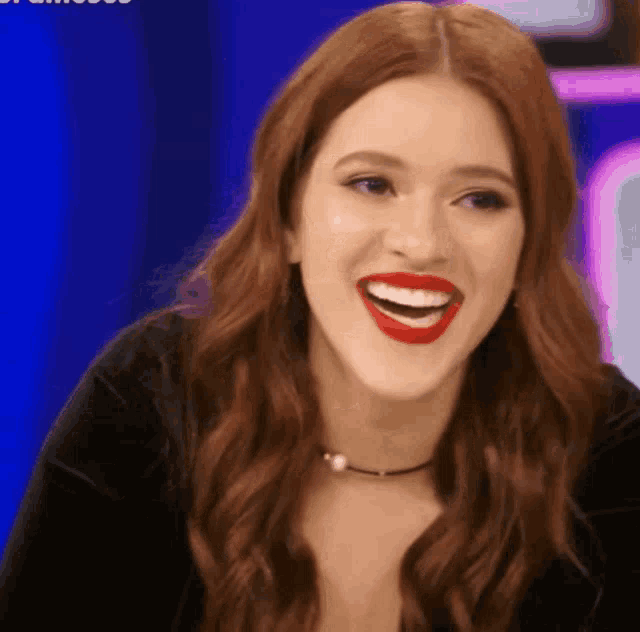 a woman with red hair and red lipstick is smiling for the camera