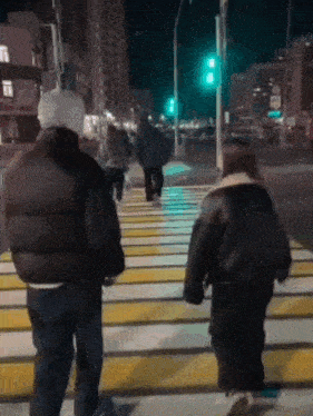 a man and a woman are crossing a street at night .