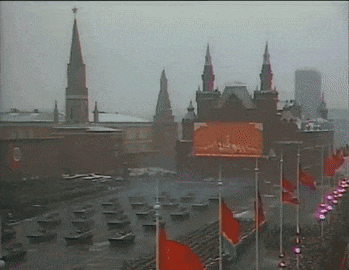 a parade in a city with a lot of red flags flying