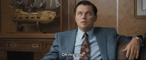 a man in a suit and tie is sitting in front of a model ship and says oh my god