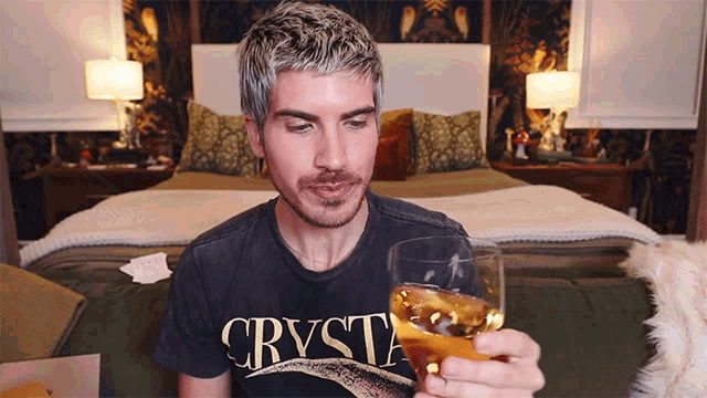 a man wearing a black shirt that says crysta holds a glass