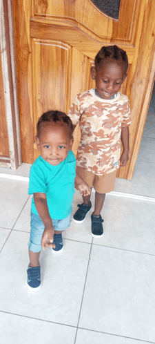 two young boys standing next to each other in front of a door