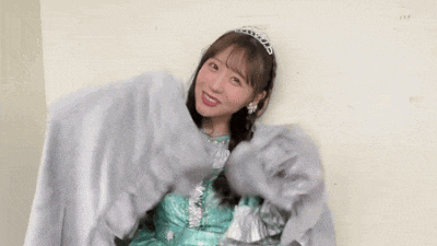 a woman wearing a tiara and a green dress is holding a blanket .