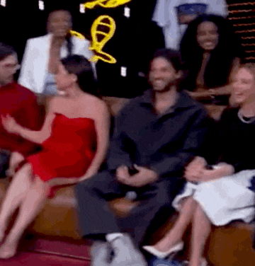 a group of people are sitting on a couch in front of a sign that says ' a ' on it