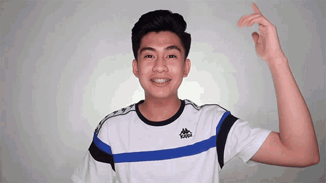 a young man wearing a kappa t-shirt is smiling