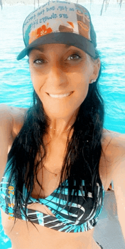 a woman in a bikini and a hat is smiling for the camera