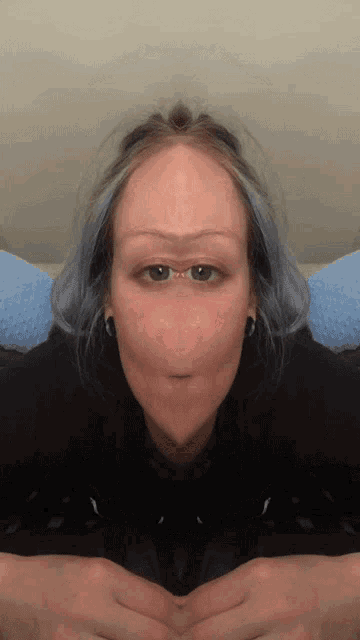 a woman with blue hair is making a funny face with her hands