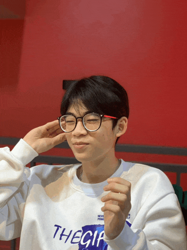 a young man wearing glasses and a sweatshirt that says thecia on it