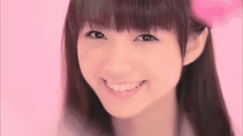 a close up of a girl 's face with a pink background and a flower in her hair .