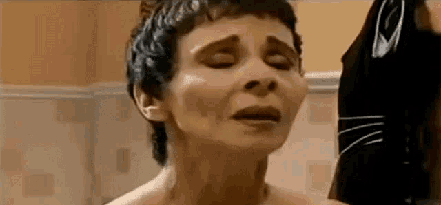 a naked woman is taking a bath in a bathroom with her eyes closed .