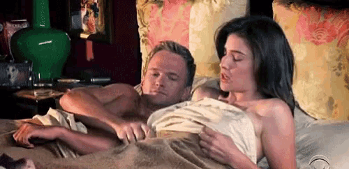 a man and a woman are laying in bed with a blanket .