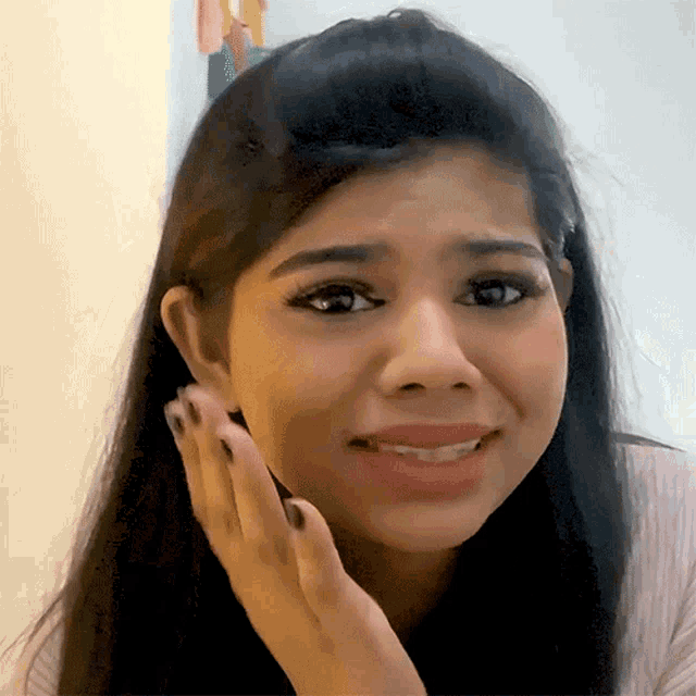 a woman with long hair is making a funny face with her hand on her face