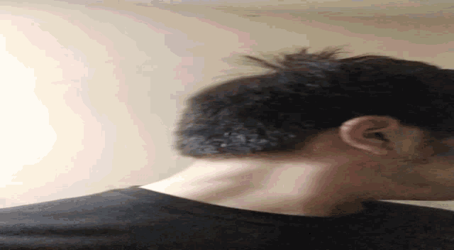 a man with a beard and a bun is looking down at his neck .