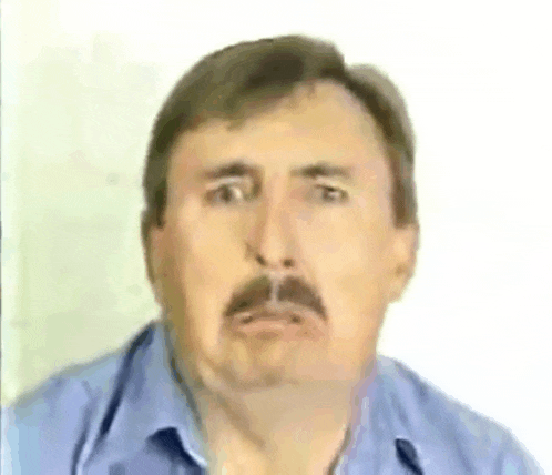 a man with a mustache is wearing a blue shirt .