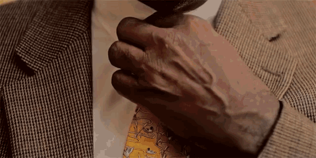a man in a suit is adjusting his tie with his hands