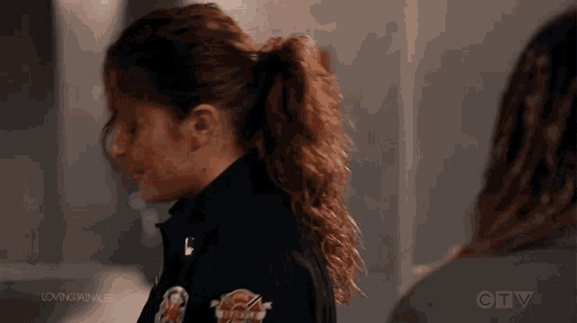 a woman in a firefighter uniform is standing next to another woman in a dark room .