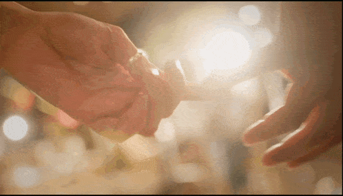 a man and woman holding hands with the sun shining through