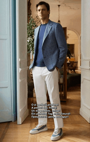 a man wearing a blue jacket and white pants is standing in a doorway