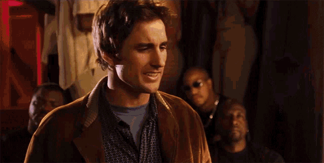 a man in a brown jacket is smiling in front of a crowd