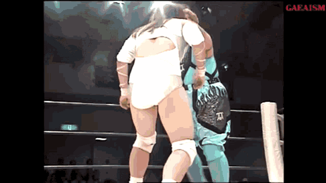 a woman in a white bodysuit is wrestling a man in a blue outfit in a ring .