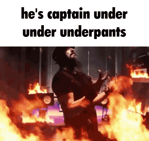 a man standing in front of a fire with the words he 's captain under under underpants written above him