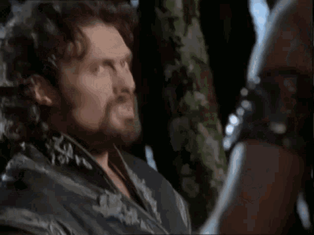 a man with a beard is talking to another man with the words stop thinking of revenge above him