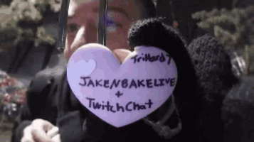 a person holding a purple heart that says jakenbakelive and twitch chat