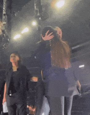 a woman covering another woman 's face with her hand while standing on a stage