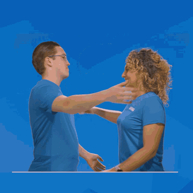 a man and a woman are hugging each other and the man has a sticker on his shirt that says ' a '