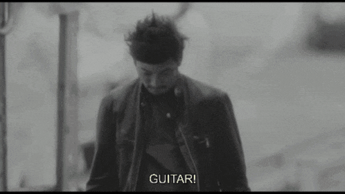 a black and white photo of a man walking down a street with the words `` guitar '' written on the bottom .
