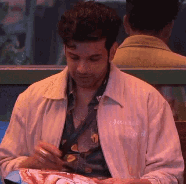 a man in a white jacket is sitting at a table in a restaurant eating food .