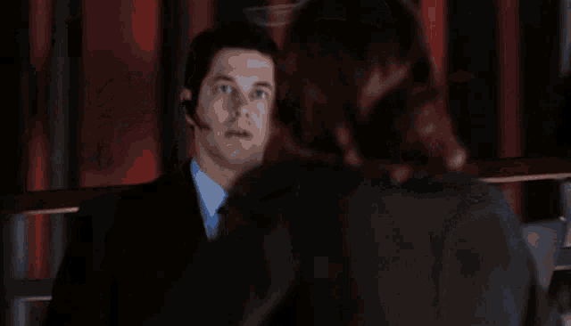 a man in a suit and tie is talking to a woman in a suit