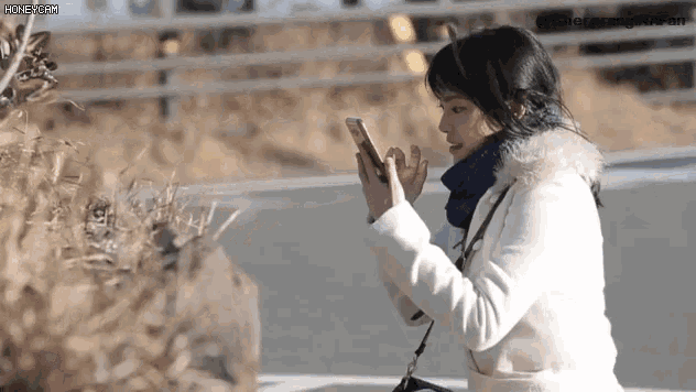 a woman is sitting on a bench looking at her phone .