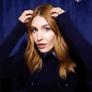 a woman with red hair is holding her hair in her hands .
