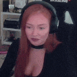 a woman with red hair wearing headphones and a choker is sitting in a chair .