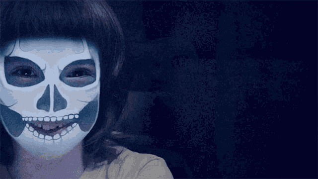 a girl with a skull painted on her face is smiling