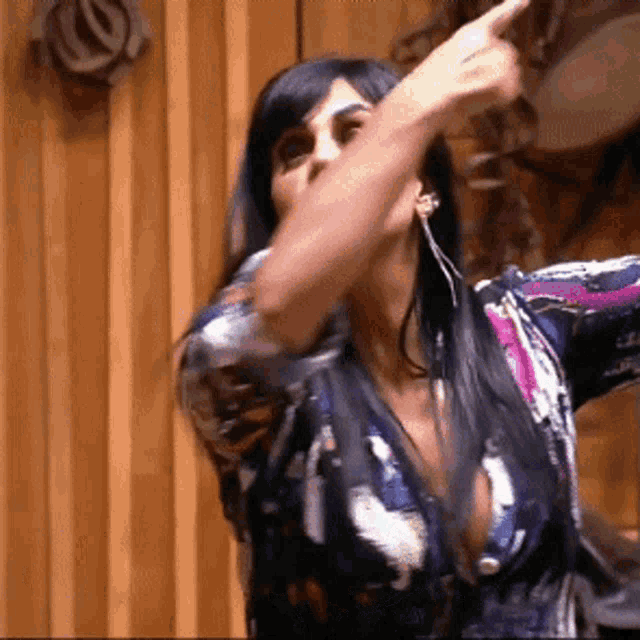 a woman in a floral shirt is pointing her finger in the air