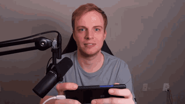 a man is holding a cell phone in front of a microphone that says nintendo on it