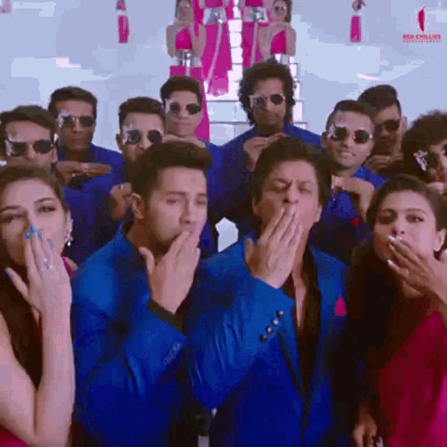 a group of people in blue suits are covering their mouths with their hands .