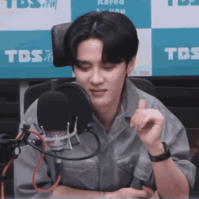 a young man is sitting in front of a microphone and making a funny face .