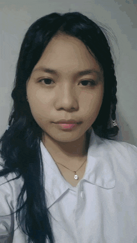 a girl with long black hair is wearing a white shirt and a gold necklace