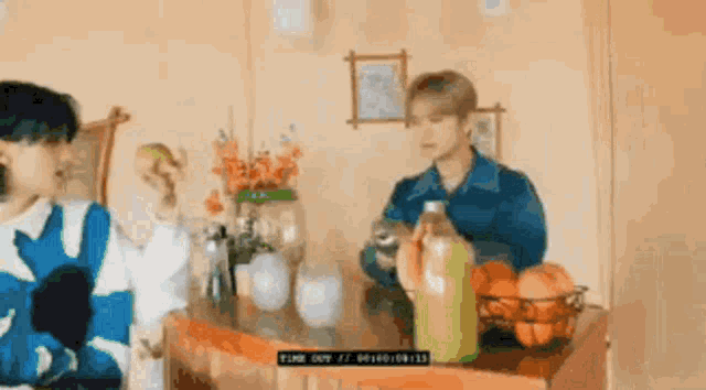 a man is sitting at a table with a bottle of orange juice and a basket of oranges .