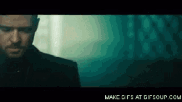 a man in a suit is standing in a dark room looking down .