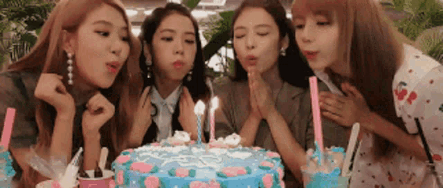 the girls are blowing out the candles on a birthday cake .