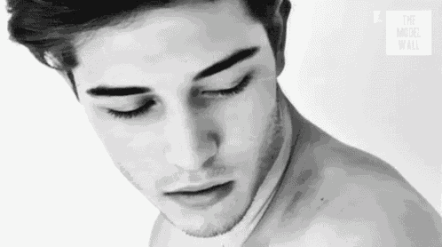 a black and white photo of a shirtless man with his eyes closed and his mouth open .