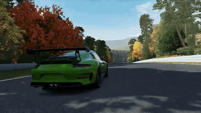 a green sports car driving down a road with trees in the background